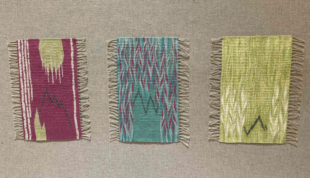 Photo of three small tapestries mounted in shades of aqua, green, pink, teal, and cream