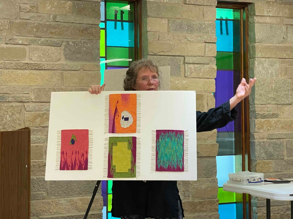 Photo of Berit Engen holding a board on which four small tapestries are mounted