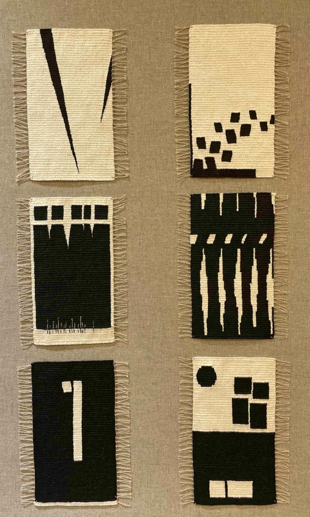 Photo of six small black and white tapestries mounted