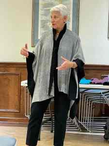 Photo of woman wearing a long wrap garment woven in shades of black and gray with insect of crimped gray cloth in front and a black crimped collar.