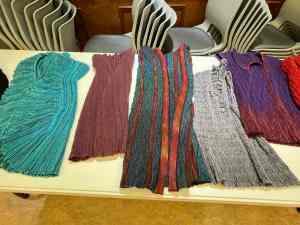 Several handwoven crimp cloth garments laid out on a table for viewing.