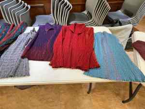 Several handwoven crimp cloth garments laid out on a table for viewing.