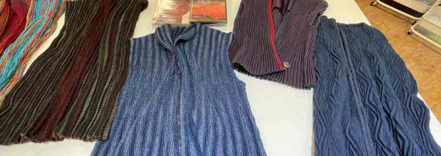 Several handwoven crimp cloth garments laid out on a table for viewing.