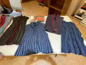 Several handwoven crimp cloth garments laid out on a table for viewing.
