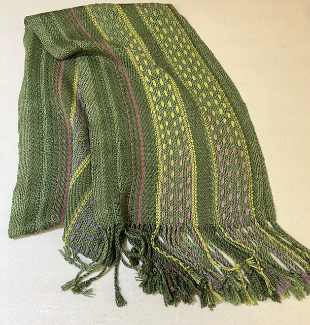 Fringed, striped scarf woven in green with striped accents in green, lavender, and orange.