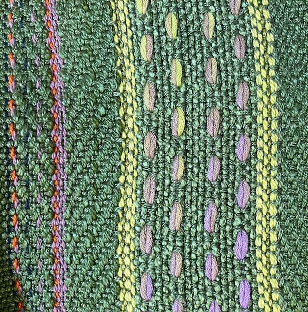 Close-up of striped scarf woven in green with striped accents in green, lavender, and orange.