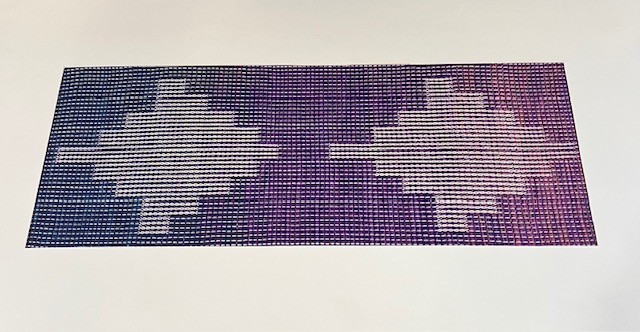 Small tapestry-like weaving in shades of blue, purple, and cream with a modern diamond-like shape. the Blue and purple colors are dominant.