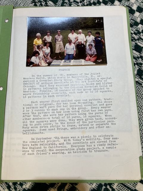 A typed page with a picture of 13 people surrounding a patterned blanket.