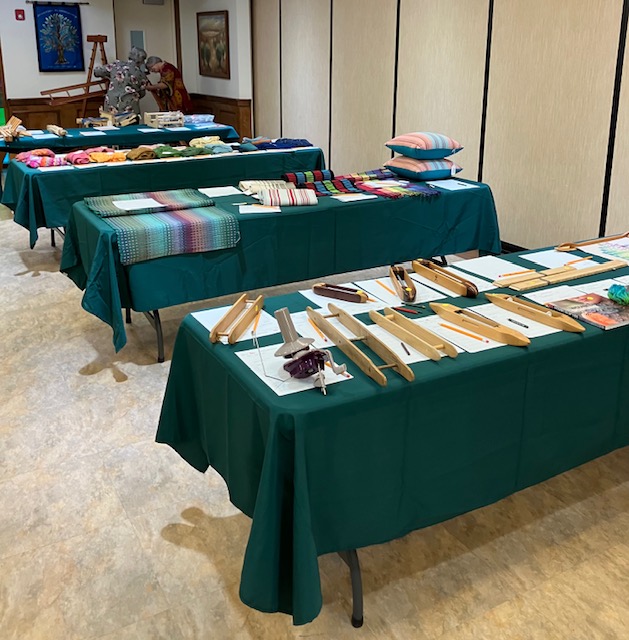 Four tables containing fiber tools and fiber products, with auction bidding sheets.