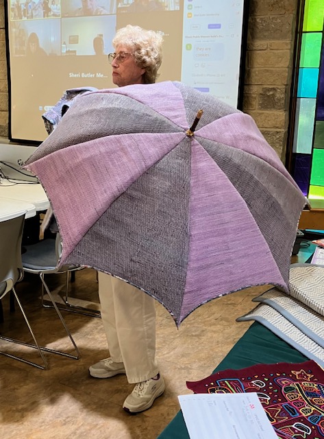 Woman holding large umbrella with alternating sections of pale purple and gray.