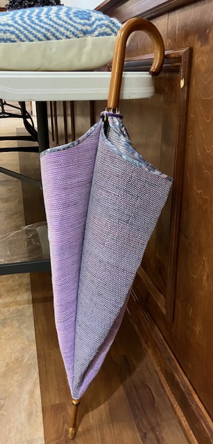 Closed umbrella showing two sections, one each of light purple and gray, and patterned fabric along the umbrella's edge.