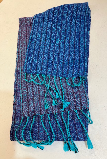 Fringed scarf with vertical stripes woven in shades of aqua, blue, and dark purple-red.