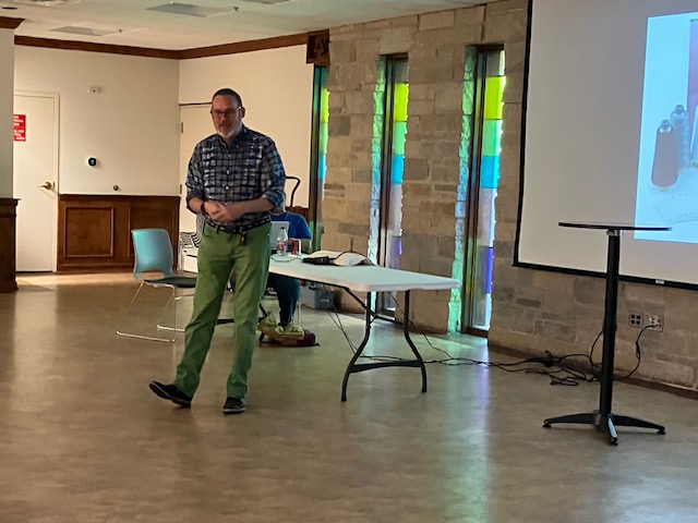 Man standing while talking in front of a projection screen