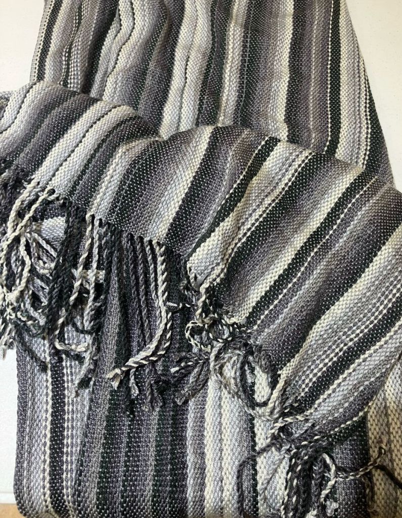 Plain weave blanket with tassels having black, white, and various shades of gray stripes.