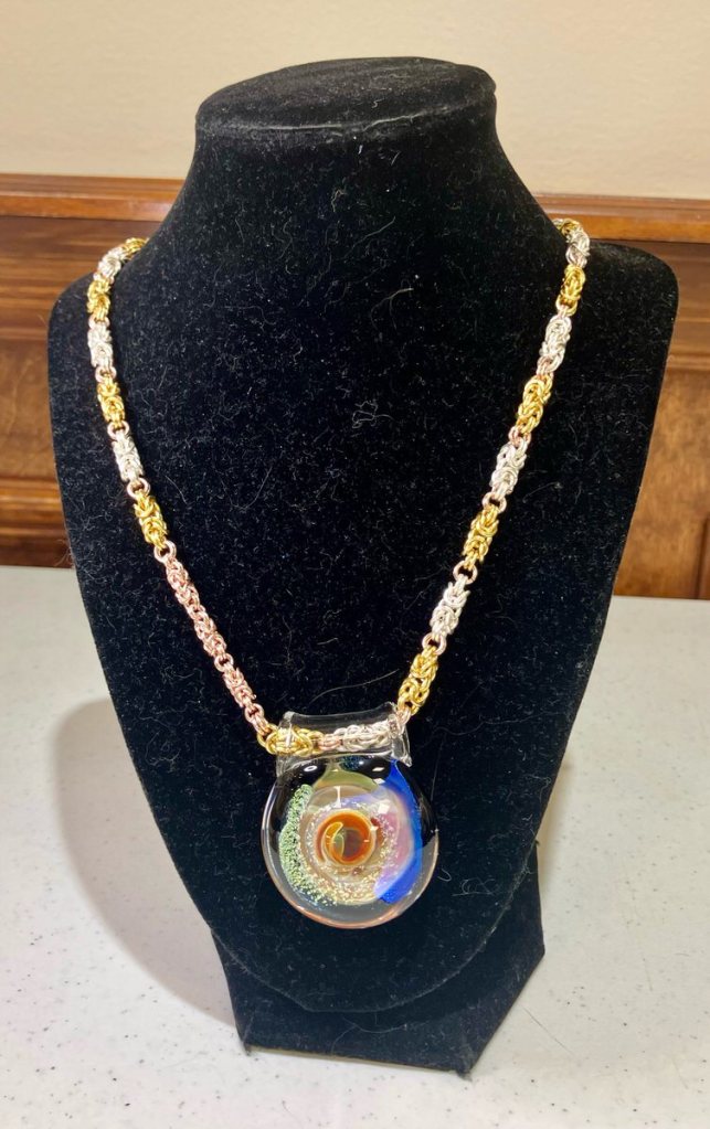 Chainmaille necklace, links in different colors with a large round focal bead.