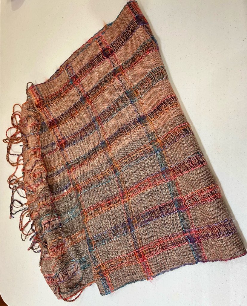 Brown, blue, and rust colored crammed and spaced shawl with fringe.