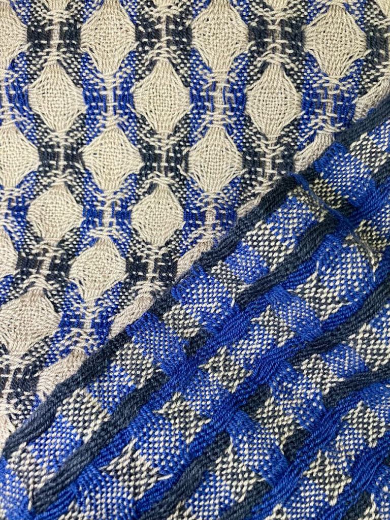 Close up. Two deflected double weave scarves in beige, blue, and navy.