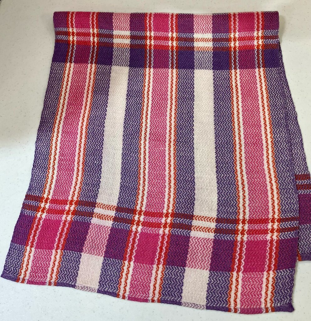 Pink, gray, red, and blue table runner with horizontal and vertical stripes.
