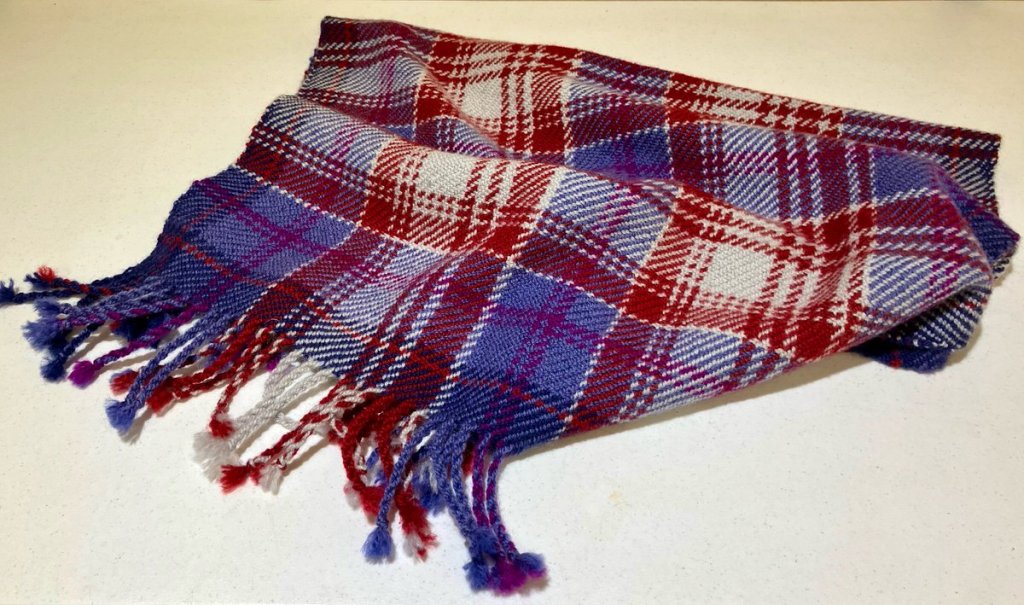 Red, white, and blue plaid car robe with fringe.