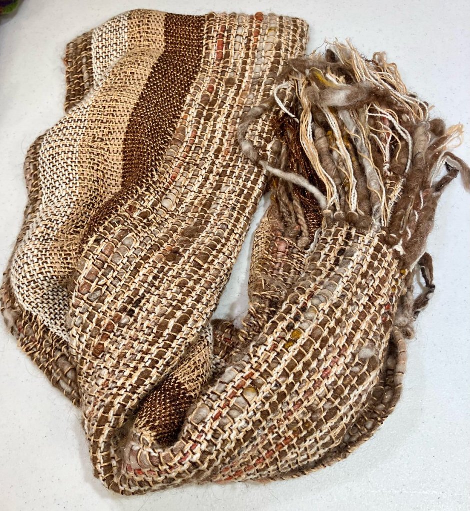 Shawl, yarns of various thicknesses in multiple shades of brown and gold with fringe.