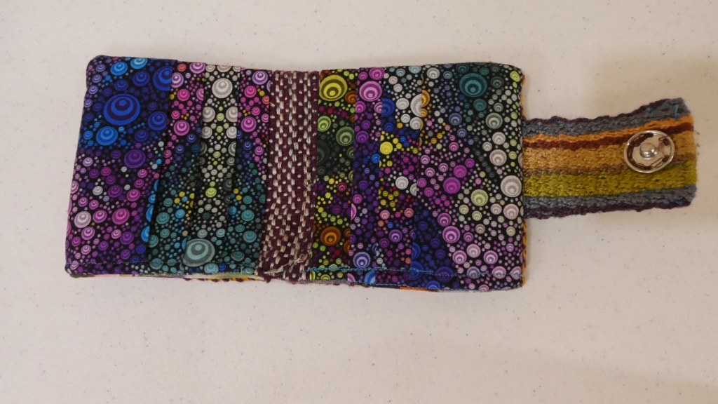 Pia T., wallet. Inside view, colorful fabric to make slots. A snap on the woven band that is used with the snap on the outer side.