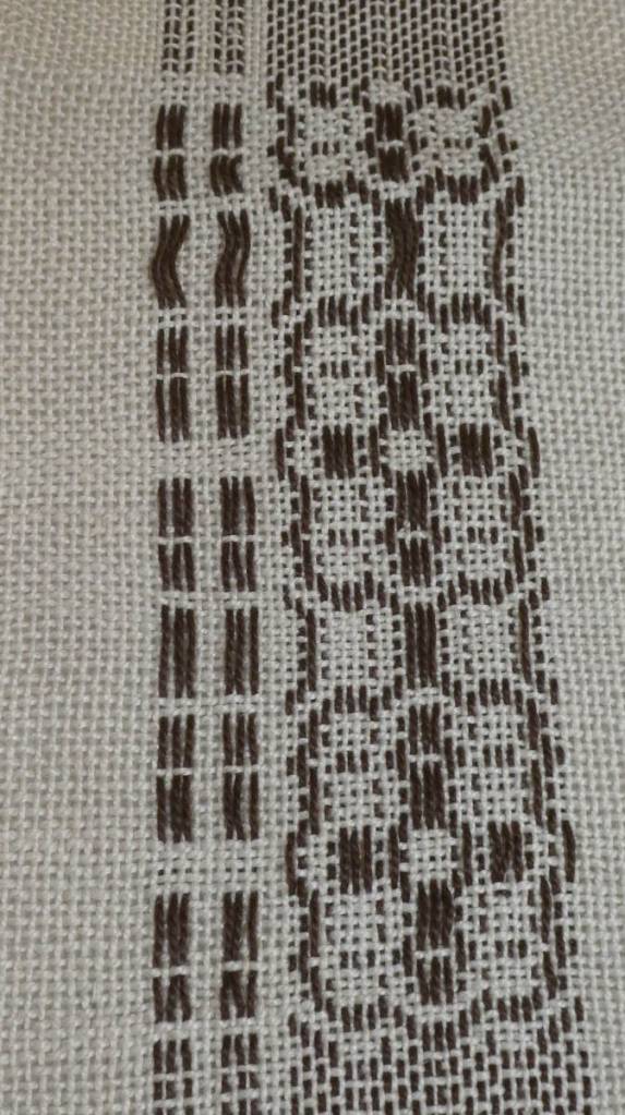 Stephanie O., sampler. Narrow strip, white background with more complex woven in black along one side.