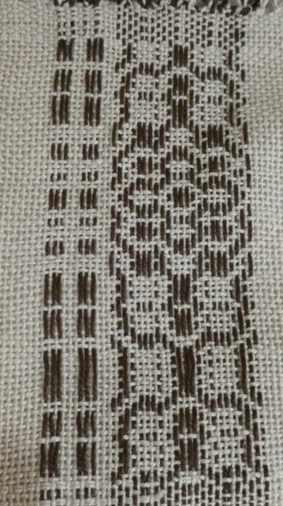Stephanie O., sampler. Narrow strip, white background with more complex woven in black along one side.