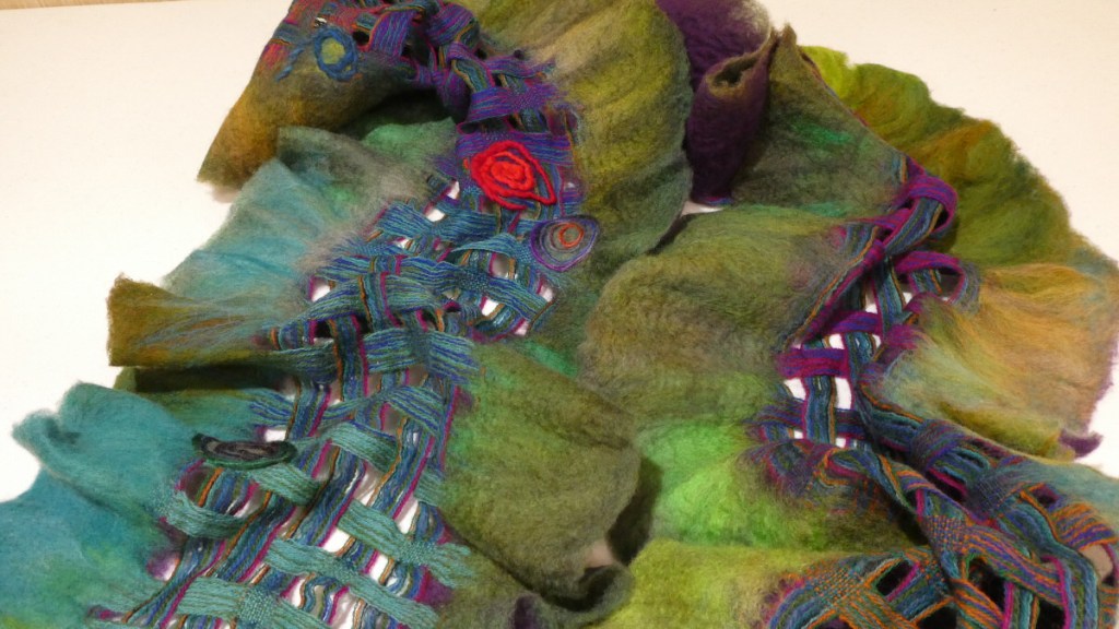 Tammy D., part of a loosely woven mostly blue and purple shawl with green felted edges and a red spiral accent.