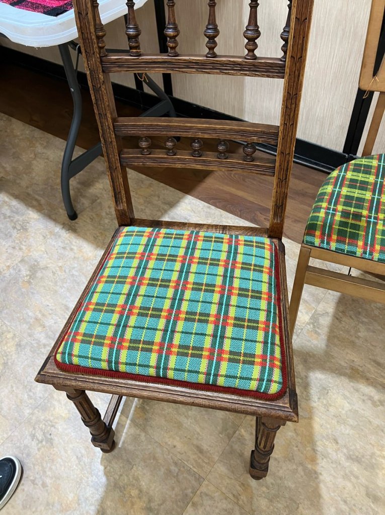 Antique wooden chair with a dark green, light green, red, and yellow plaid seat cover.