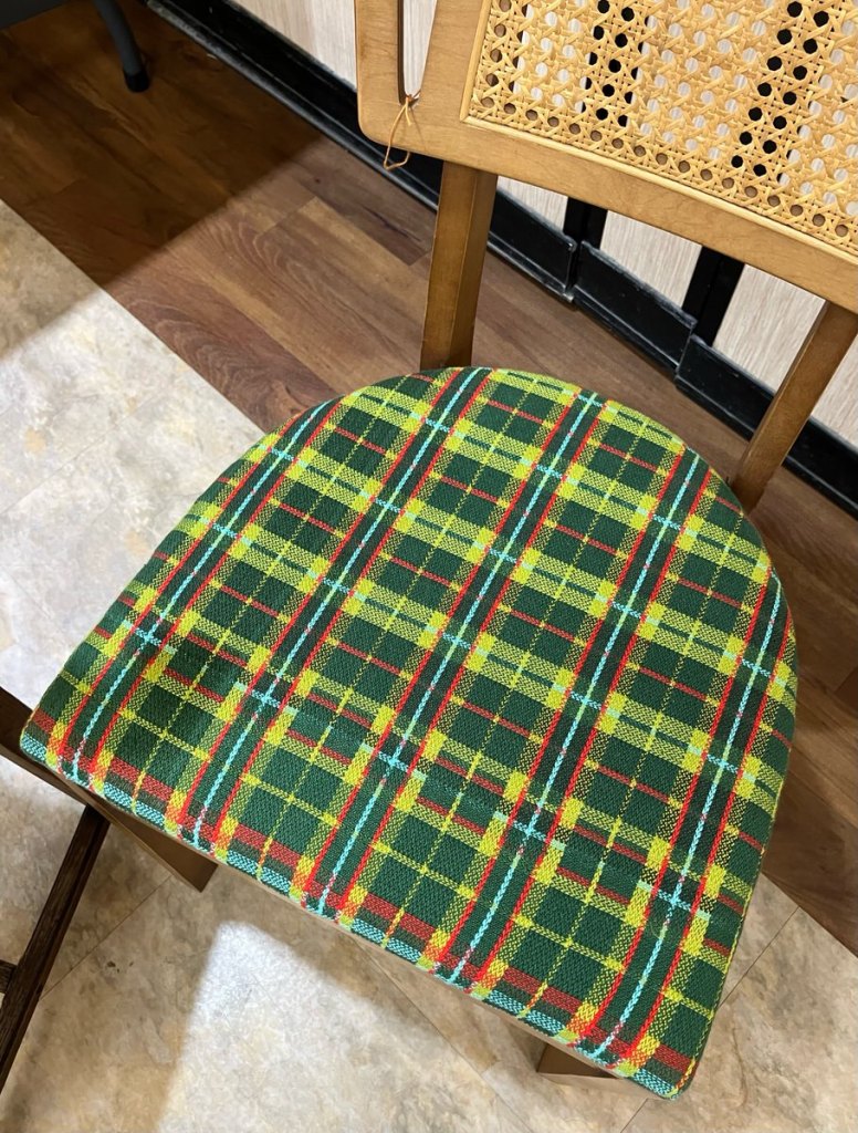 Chair with a dark green, light green, red, and yellow plaid seat cover.