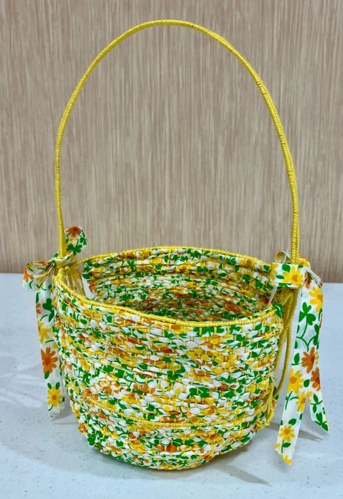 Floral fabric woven into a basket with a thin yellow handle.