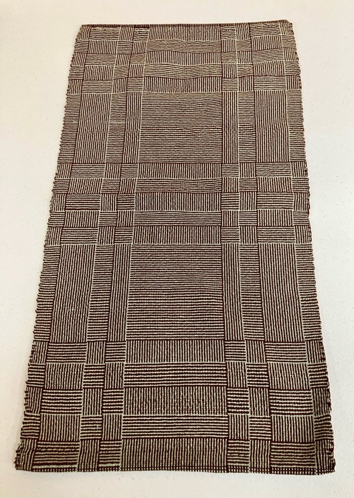 Patterned table runner woven in shades of cream and brown.