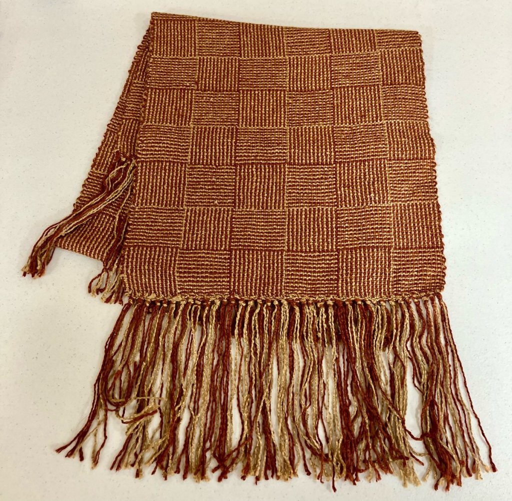 Fringed, patterned scarf woven in shades of dark red and tan