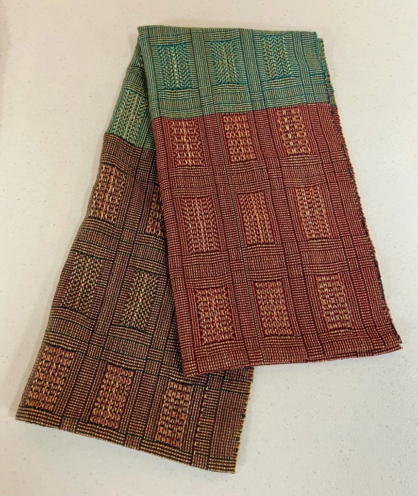Patterned towel woven in shades of red, green, and brown with staggered rectangular motifs