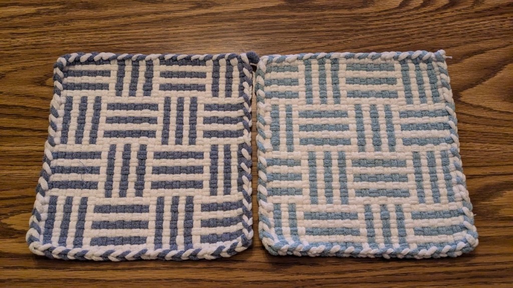 Two patterned square potholders woven in shades of blue and white