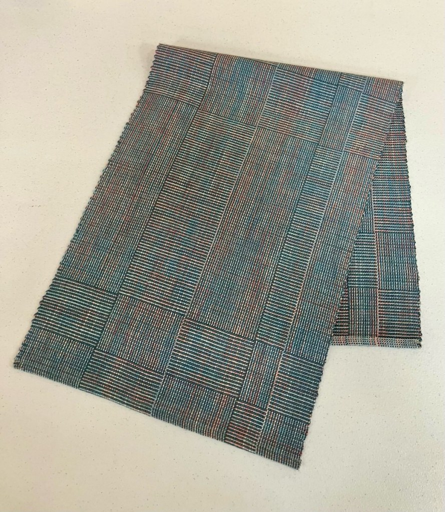 Patterned table runner woven with multiple colors including blue, cream, and pink