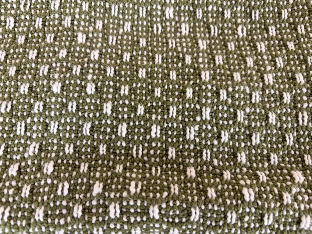 Close-up of towel woven in dark olive green and cream.
