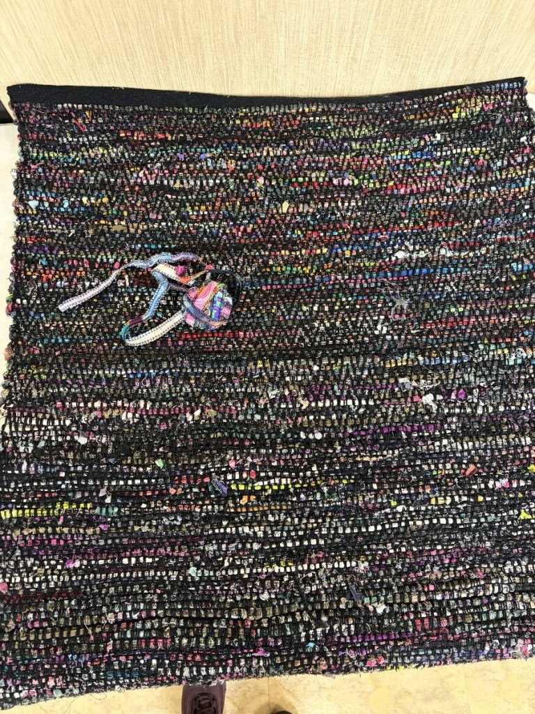 Woven throw rug in shades of black and bright colors