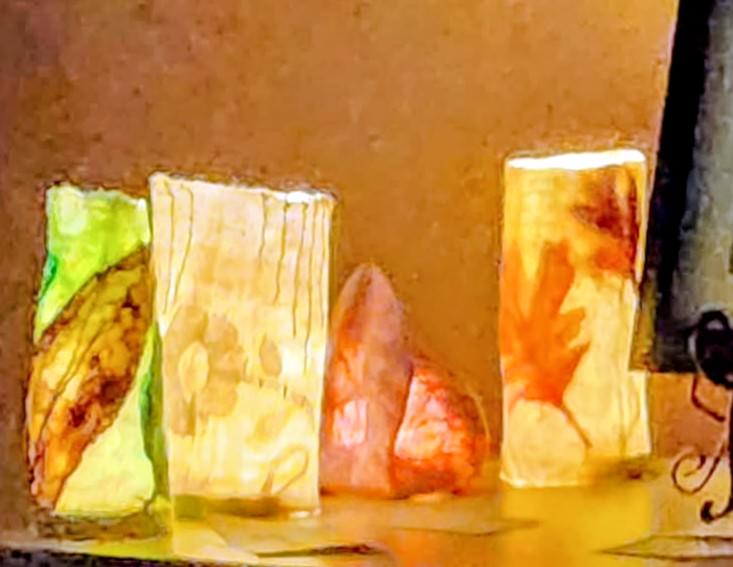 Four felt luminaries with embedded leaves and other designs.