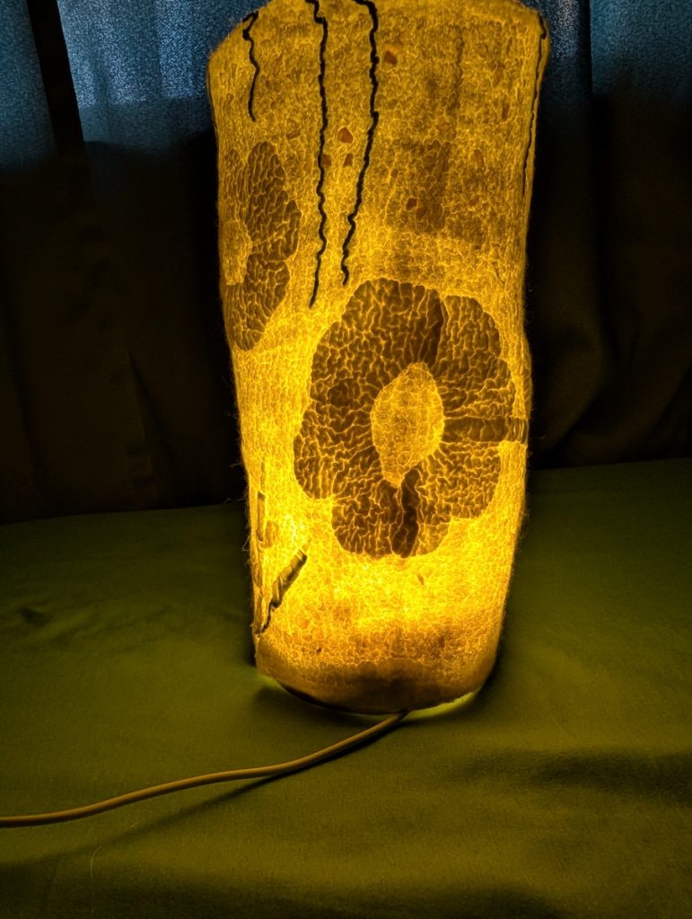 Luminary 1. Lit. Columnar, off-white, with a floral design in it.