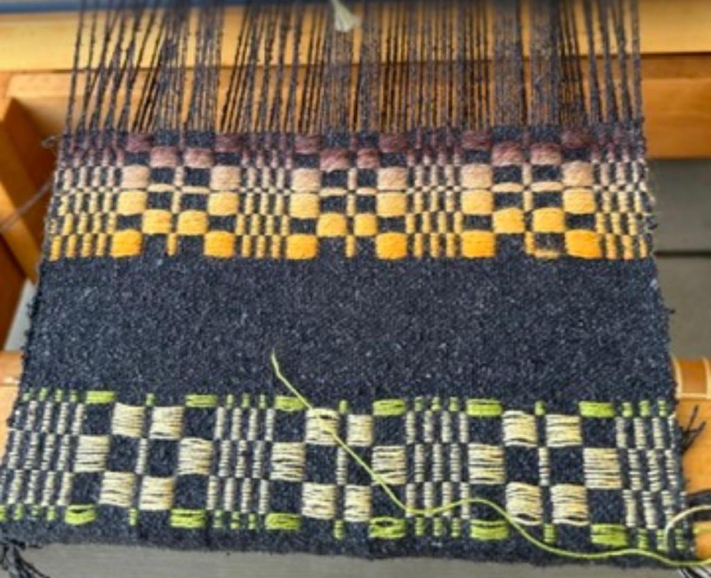 Monk's belt weaving done in bright colors on a dark blue warp.