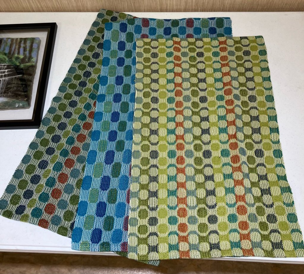 Three multi-colored turned taquete towels with circle and oval motifs.