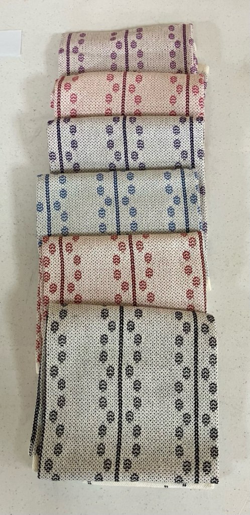 Towels, different colors, having a series of straight lines with circular motifs on each side of the line.