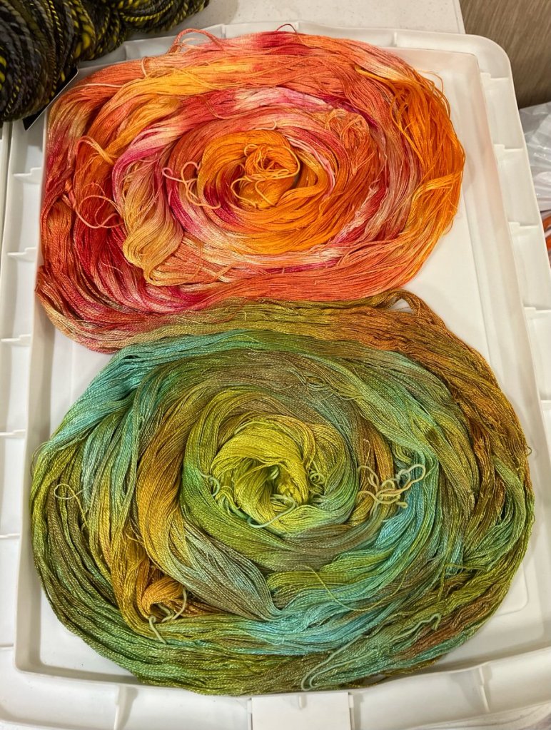 Painted warp coils, in orange and red and in green, blue, and brownish yellow.