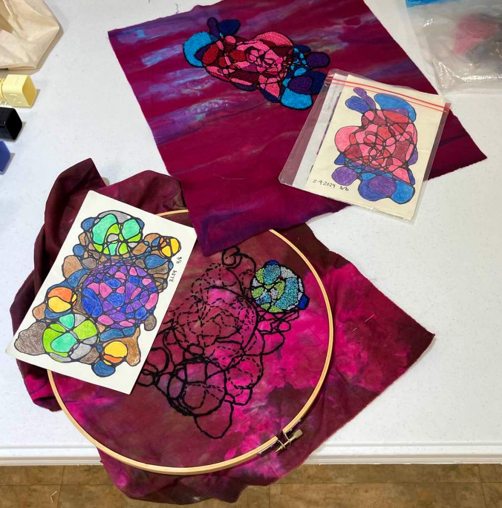 Tammy D. - Embroidered abstract shapes, outlined in black, using bright colors on a dark pink and maroon mottled background.