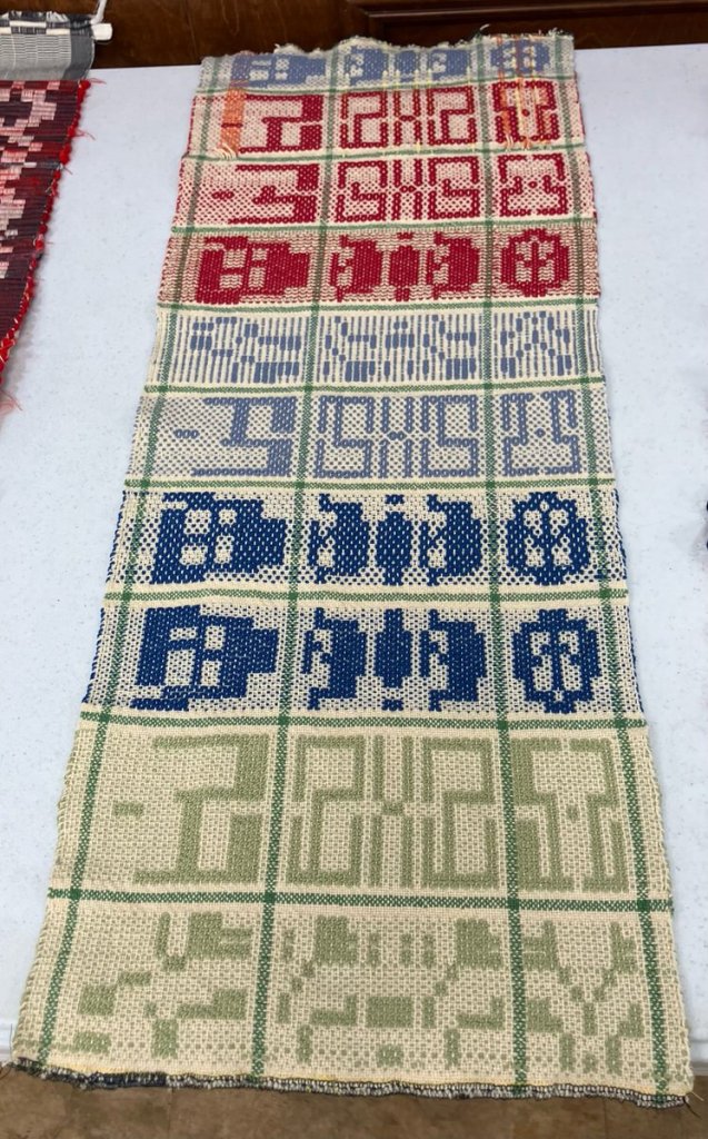 Fabric done in three blocks across with red, light blue, blue, and light green on a light neutral background.