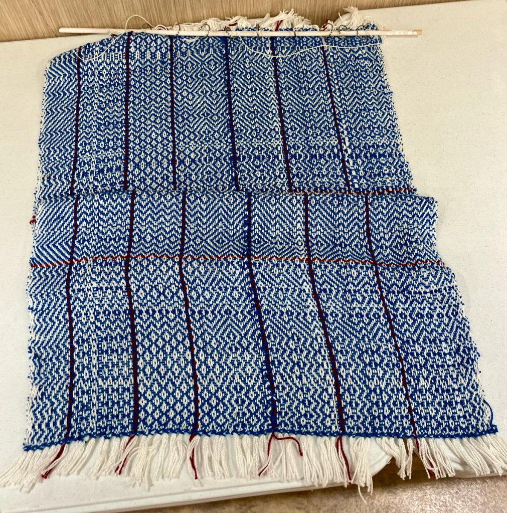 Hal W. - Dark blue twill done on a white warp that has very thin stripes of red.