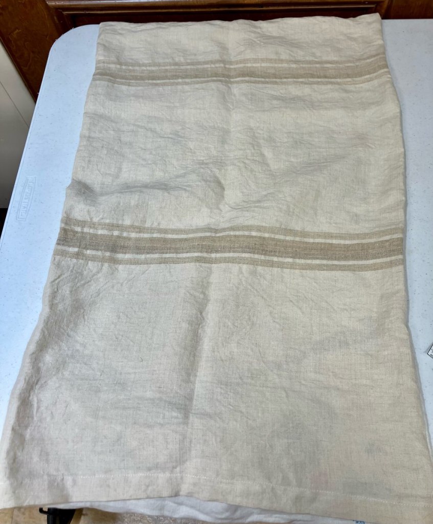 Sarah B. - Off-white piece of rectangular fabric with two sets of small brown stripes.
