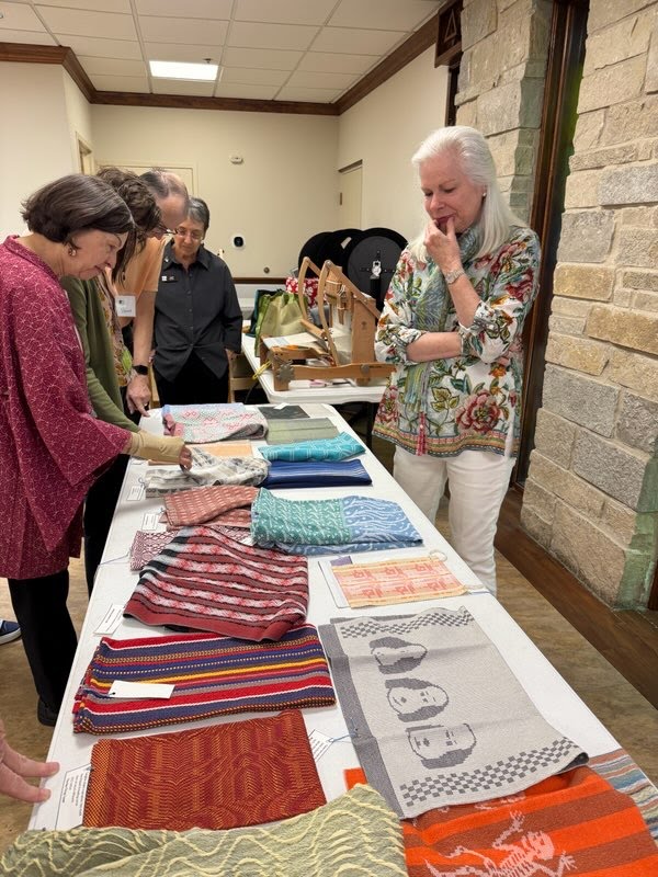 Several people around a table with handwoven samples.