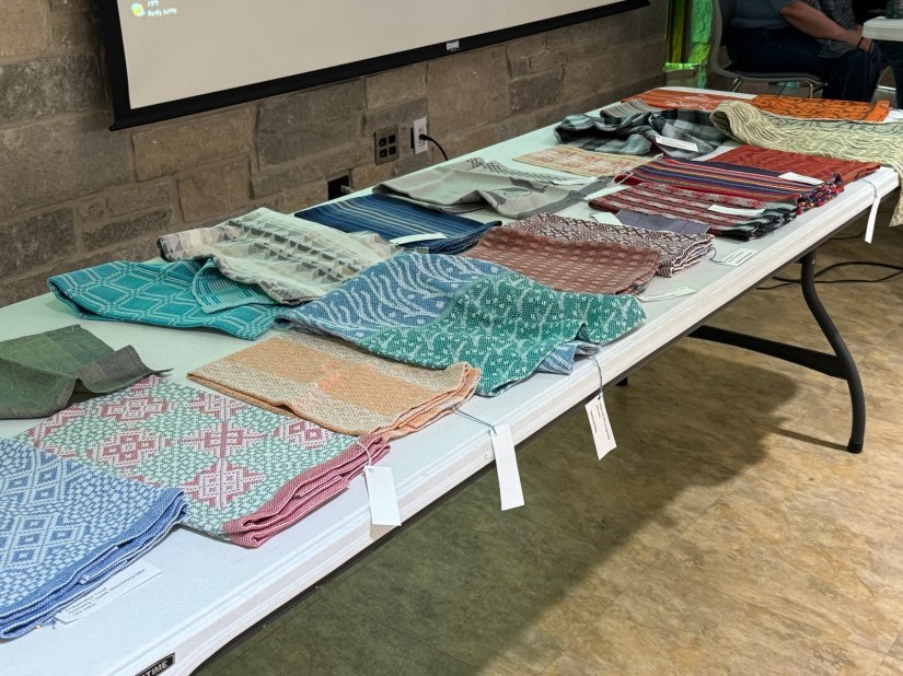 Many handwoven textiles laid out on a table